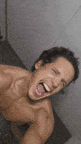 a shirtless man taking a selfie with his mouth wide open