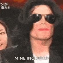 michael jackson is wearing sunglasses and making a funny face while talking to a woman .
