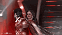 a man is holding a woman in his arms while they are dancing on a stage .