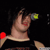 a man singing into a microphone with the word bloggif on the bottom right corner