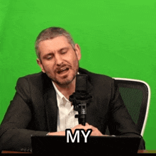 a man in a suit is singing into a microphone with the word my above him .