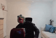 a man wearing a frog mask is sitting in a chair in a living room