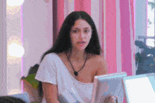 a woman in a white shirt is sitting in front of a computer monitor .