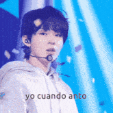a young man wearing a microphone and a hoodie with the words yo cuando anto written below him .