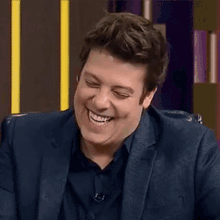 a man in a suit and black shirt is laughing and smiling .