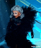a drag queen wearing a black dress with feathers on her wings