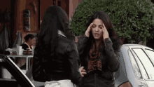 two women are standing next to each other and one is holding her head