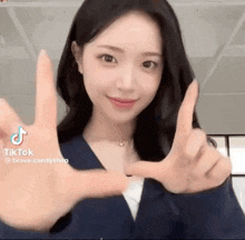 a woman is making a peace sign with her hands while wearing a blue jacket .