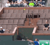 a man in a blue shirt is holding a tennis racquet in front of a bnp bank sign