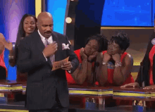 a man in a suit and tie stands in front of a group of women