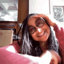 a woman wearing glasses is smiling and holding her head