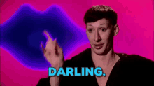 a man is giving the middle finger in front of a pink background with the word darling .
