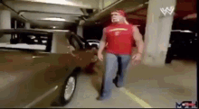 a man in a red tank top is walking in a parking garage .