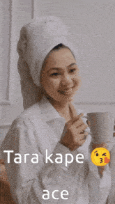 a woman with a towel wrapped around her head is holding a cup of tea
