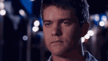 a close up of a man 's face with a blurry background of lights .