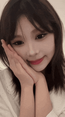 a woman with her hand on her face looks at the camera