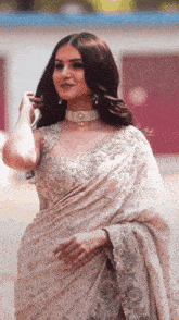 a woman is wearing a white saree and a choker .