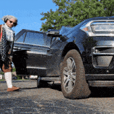 a man in a costume stands next to a black suv