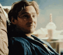 a man in a blue jacket is sitting in a chair with his head resting on his arm