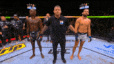 a referee stands between two fighters in a boxing ring with ufc written on the ground
