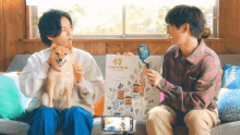 two men sitting on a couch holding a sign that says 47