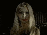 a woman with long blonde hair is making a hand gesture in front of her face .