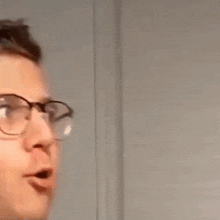 a man wearing glasses is making a funny face and looking at the camera .