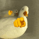 a white duck with a yellow thumb pointing at the camera