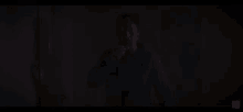a man in a blue shirt is standing in the dark and pointing at something .