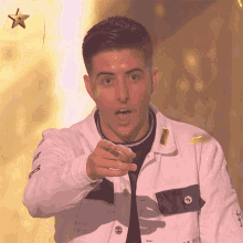 a man wearing a white jacket with the letters s on it points at the camera