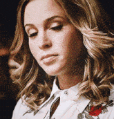 a close up of a woman wearing a white shirt with a red rose on it