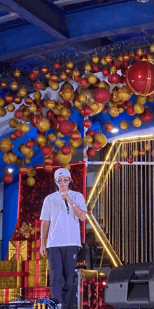 a man singing into a microphone with christmas decorations hanging from the ceiling behind him