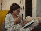 a woman is sitting on a couch reading a book and eating food