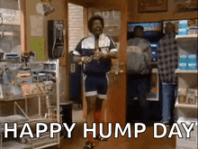 a man is dancing in a store with the words `` happy hump day '' written on the screen .