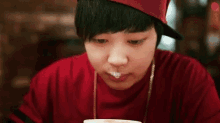 a young man wearing a red shirt and a red hat is eating ice cream .