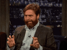 a man with a beard and a suit is making a funny face and sticking his tongue out .