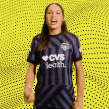 a woman wearing a purple cvs health jersey is cheering