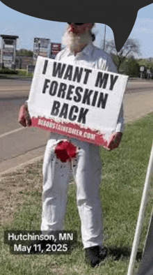 a man holding a sign that says i want my foreskin back
