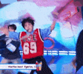 a person wearing a red jersey with the number 69 on it is dancing on a stage .
