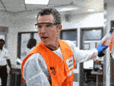 a man wearing a white shirt and an orange vest that says workers emergency