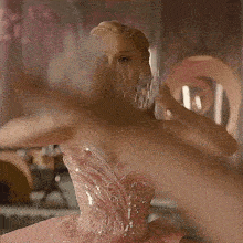 a woman in a pink dress is holding a crown on her head