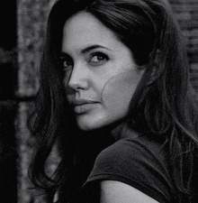 a black and white photo of a woman with long hair looking over her shoulder