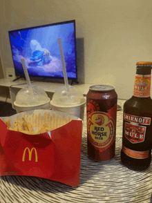 a bottle of smirnoff mule sits on a table next to a can of red horse beer