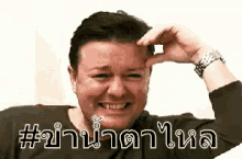 a man is scratching his forehead with his hand and smiling in a foreign language .