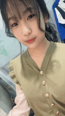 a young girl wearing a green cardigan with gold buttons