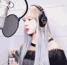 a woman wearing a pair of sony headphones stands in front of a microphone