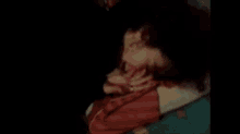 a woman is laying on a bed with her eyes closed and a man is holding her hand .