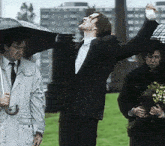 a man in a suit is holding an umbrella in the air