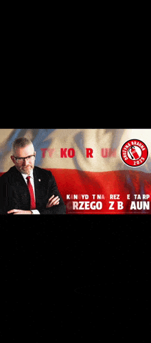 a man in a suit and tie is sitting in front of a flag with the words tylko r un written on it