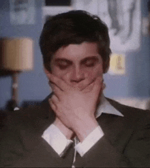 a close up of a man covering his mouth with his hands .
